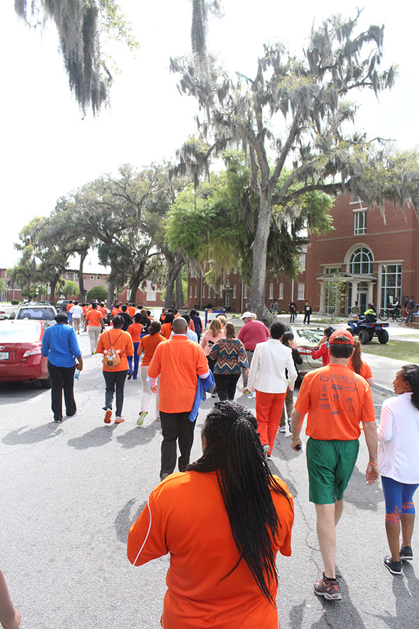 Savannah State University employees walk by large moss-covered trees during campus fitness walk.