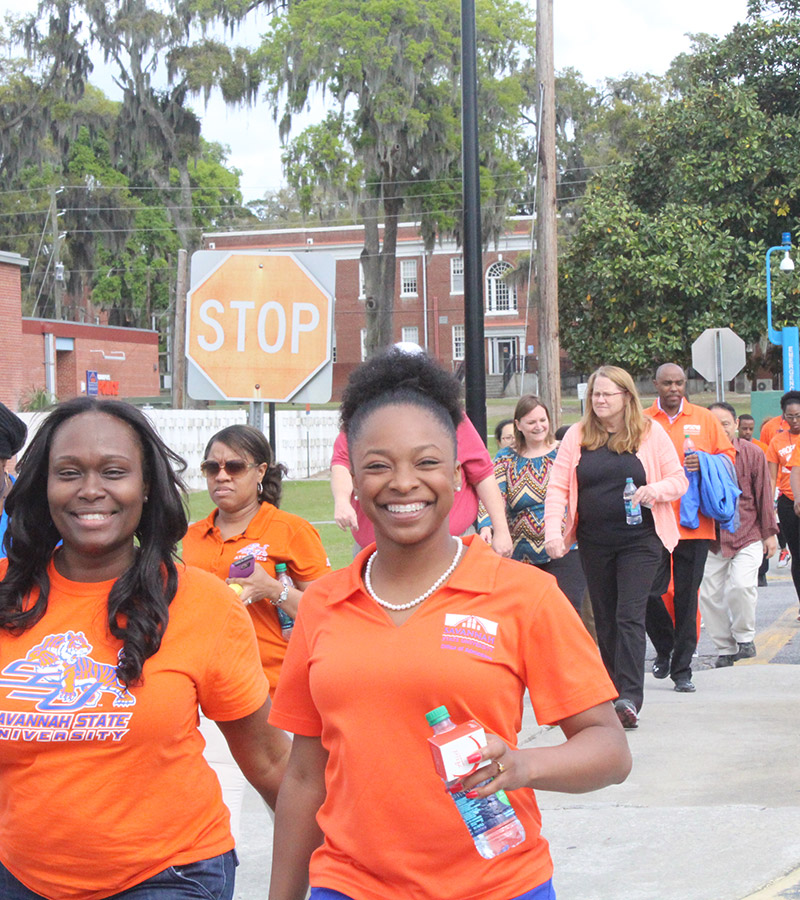 Savannah State University employees in orange shirts taking part in the walk challenge.